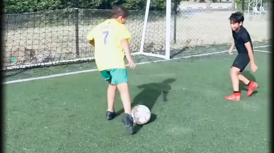 Partie de football entre enfants, filmée en plan large.